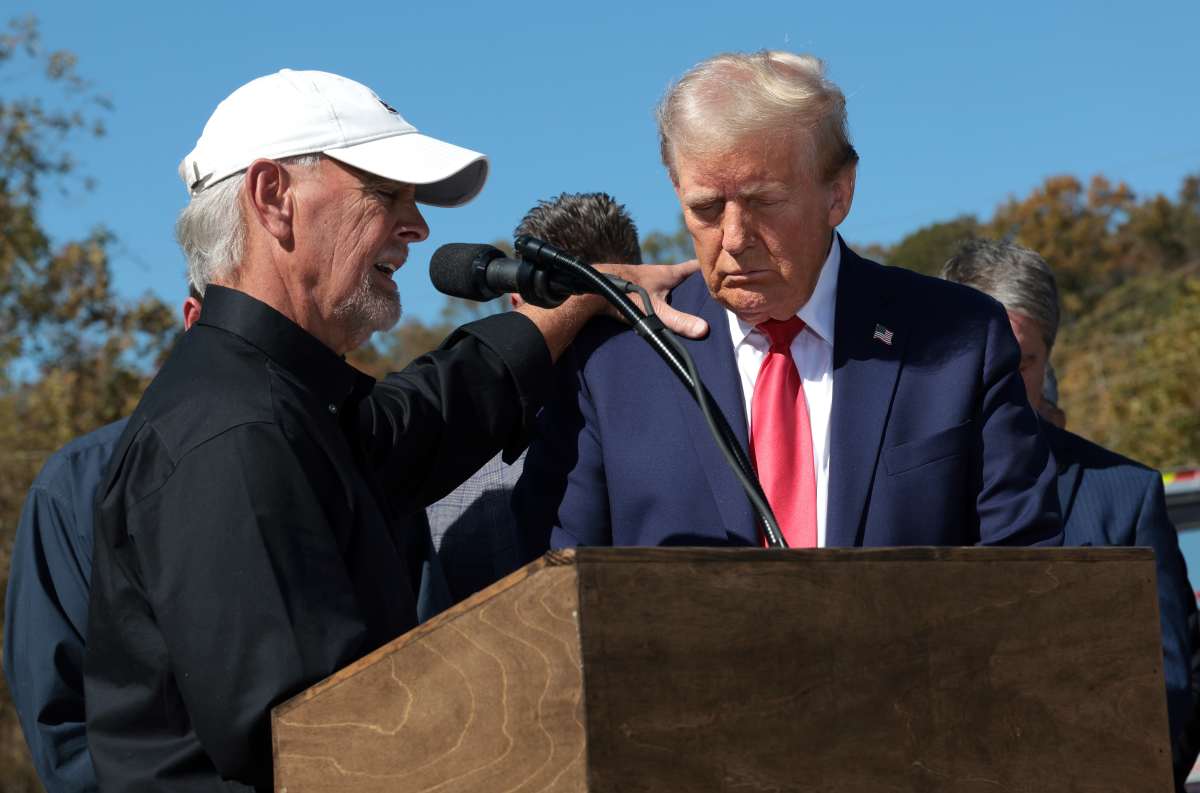 Mike Stewart, a local resident impacted by Hurricane Helene, prays with Republican presidential nominee, Donald Trump, as he tours a neighborhood affected by the hurricane on October 21, 2024. (Image Source: Getty Images | Photo by Win McNamee)