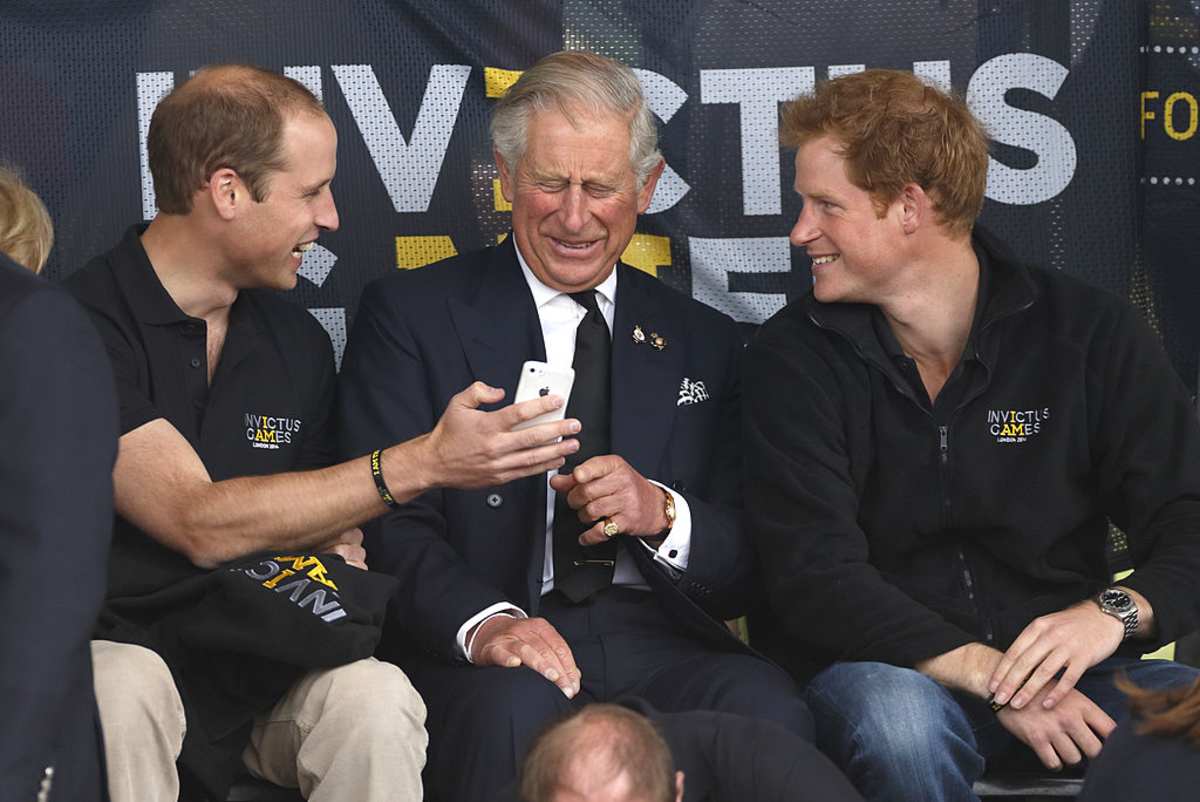 Prince William, Duke of Cambridge, Prince Charles, Prince of Wales & Prince Harry look at a mobile phone. (Image Source: Photo by Max Mumby / Getty Images)