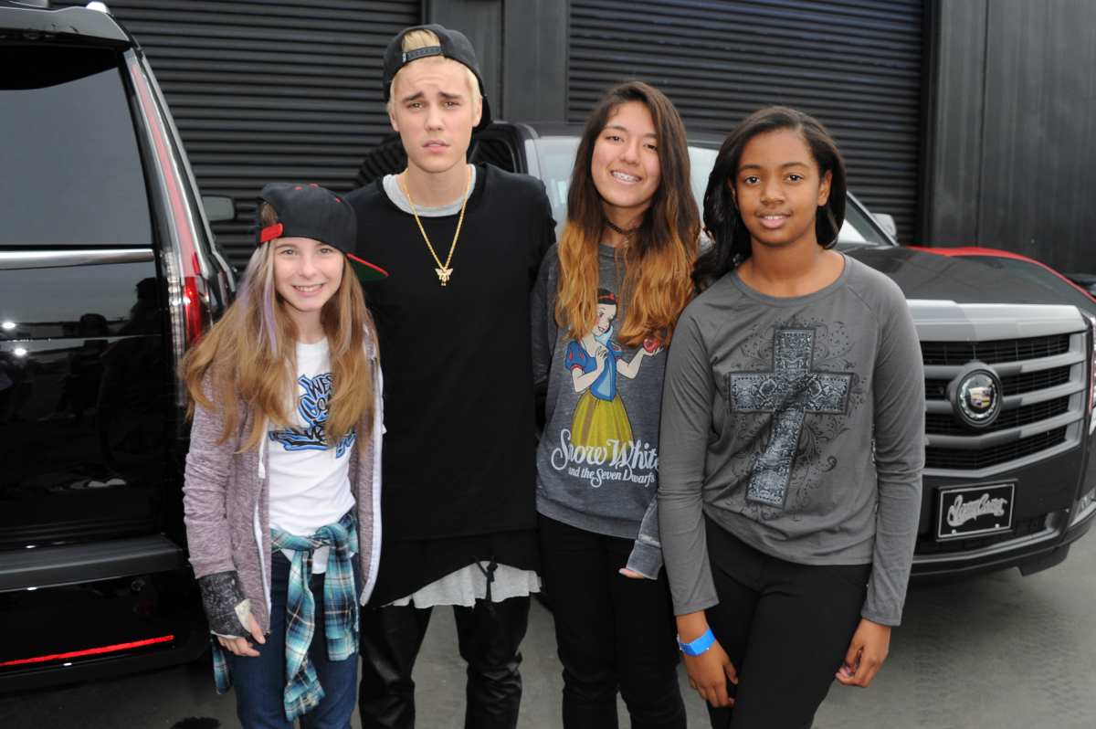 Justin Bieber poses for a picture with young fans during the Grand Opening of West Coast Customs Burbank Headquarters. (Image Source): Getty Images | Photo by Allen Berezovsky