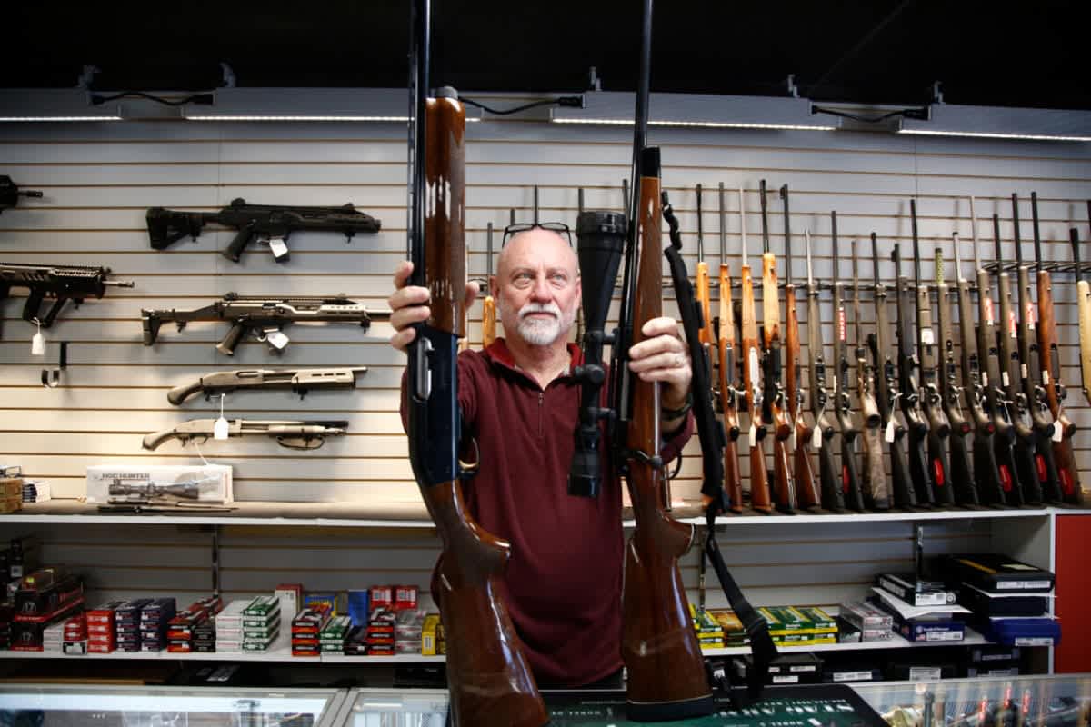 Bret Reid shows off a Remington 700 hunting rifle and a Remington 1100 shotgun available for sale at Atlantic Outdoors gun shop on March 26, 2018, in North Carolina. (Image Source: Getty Images | Photo by Brian Blanco)