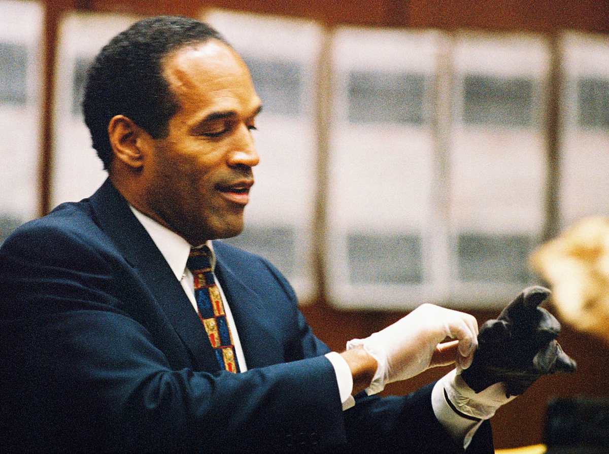 O.J. Simpson tries on a leather glove allegedly used in the murders of Nicole Brown Simpson and Ronald Goldman in 1995 in Los Angeles. (Image Source: Getty Images | Photo by Lee Celano)